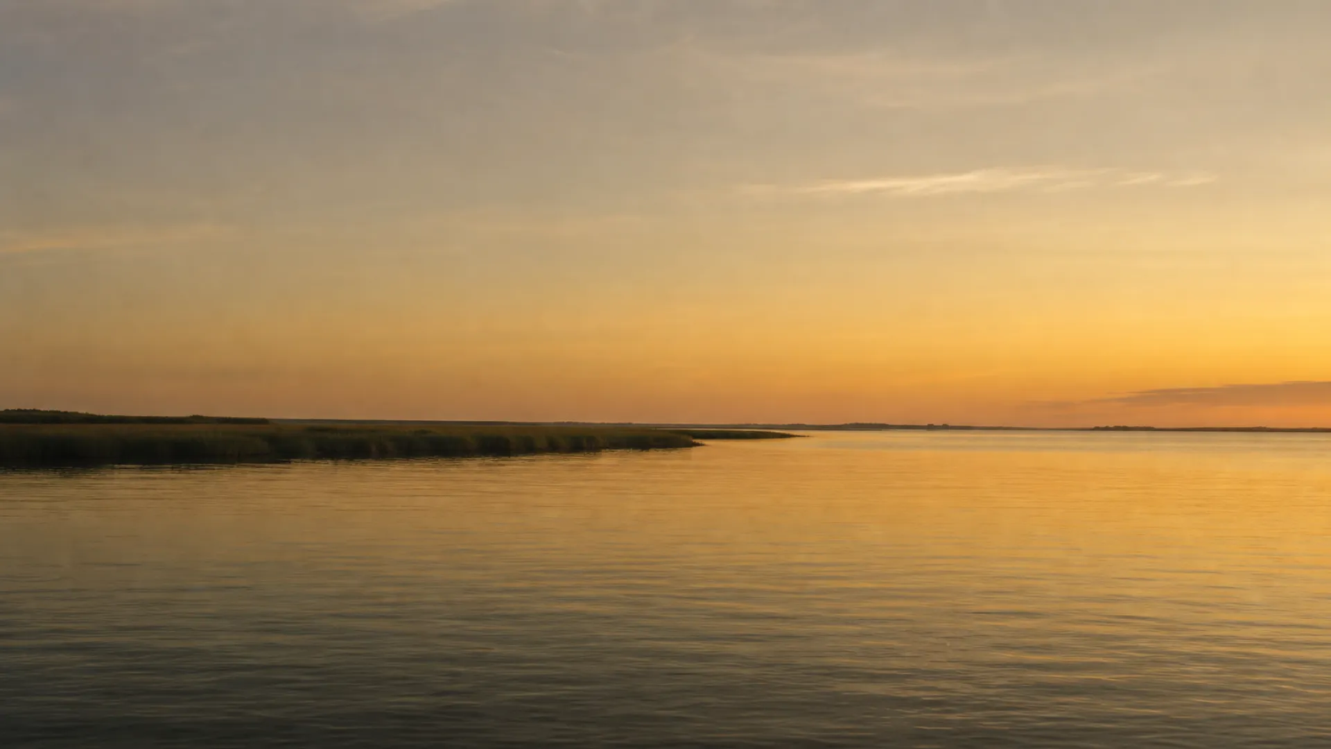 Wide, still harbor water under a soft, open morning sky.