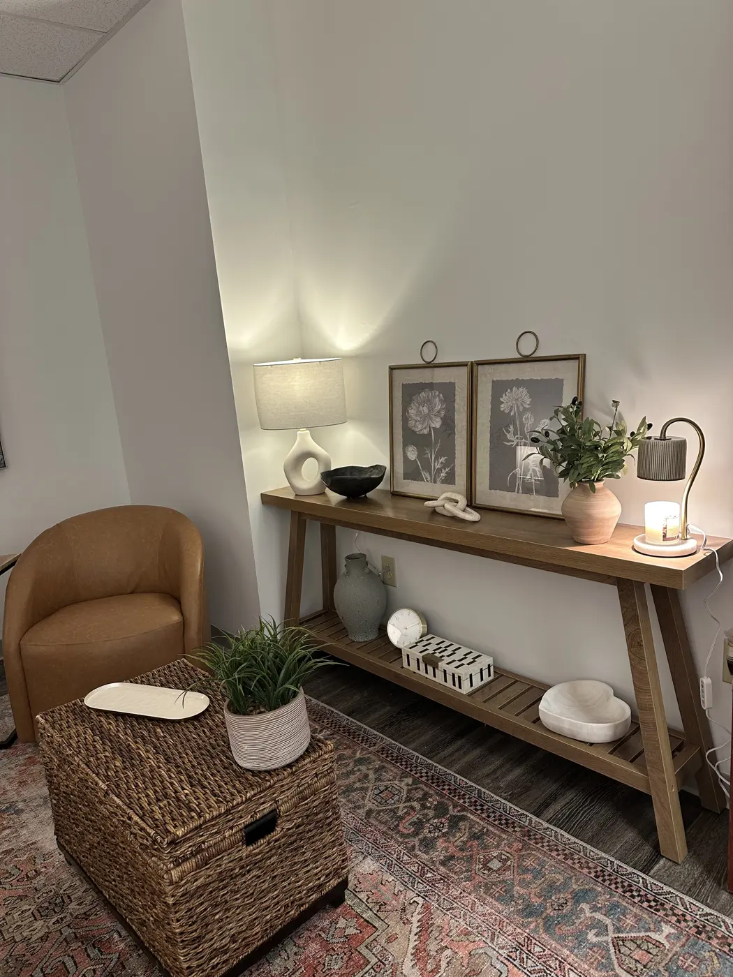 A console table in Patti's office with framed prints, plants, and warm lamp light.